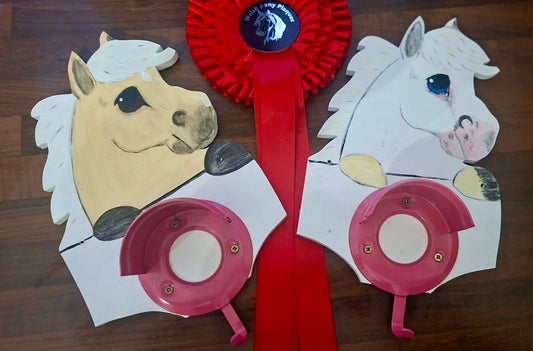 Two horse-shaped cutouts with a red ribbon on a wooden surface