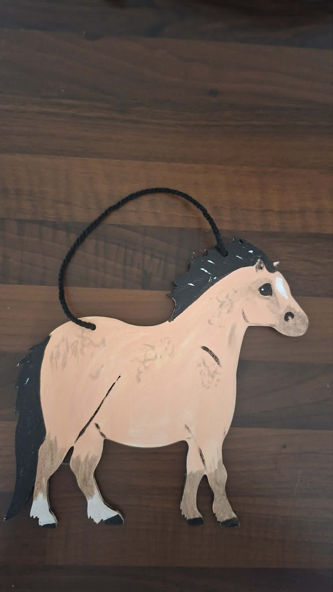 Wooden horse ornament hanging on a wooden surface