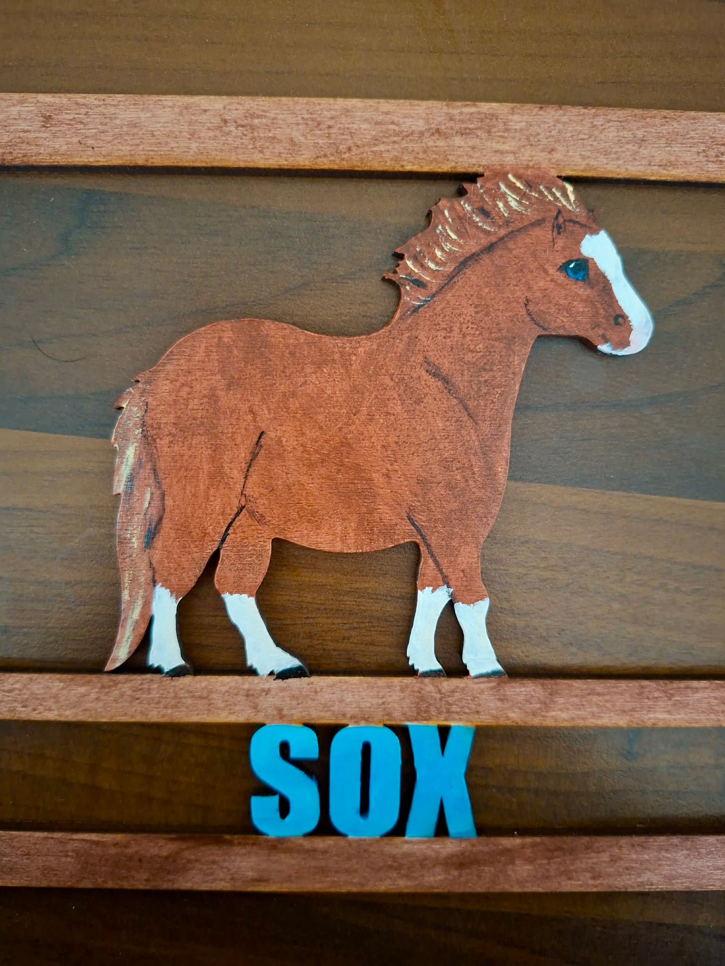 Wooden horse cutout with 'SOX' on a wooden surface