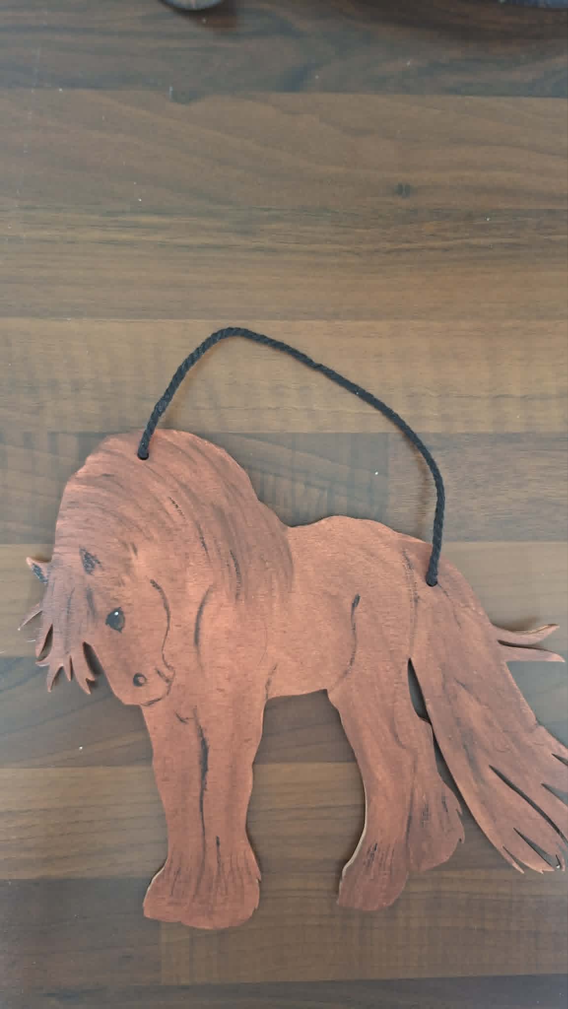 Wooden horse ornament hanging on a wooden surface