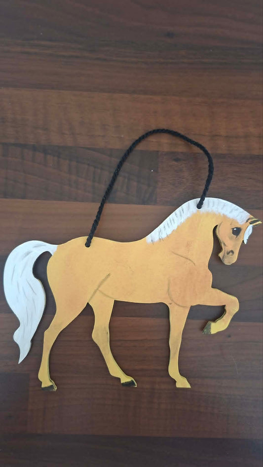 Wooden horse ornament hanging on a wooden surface